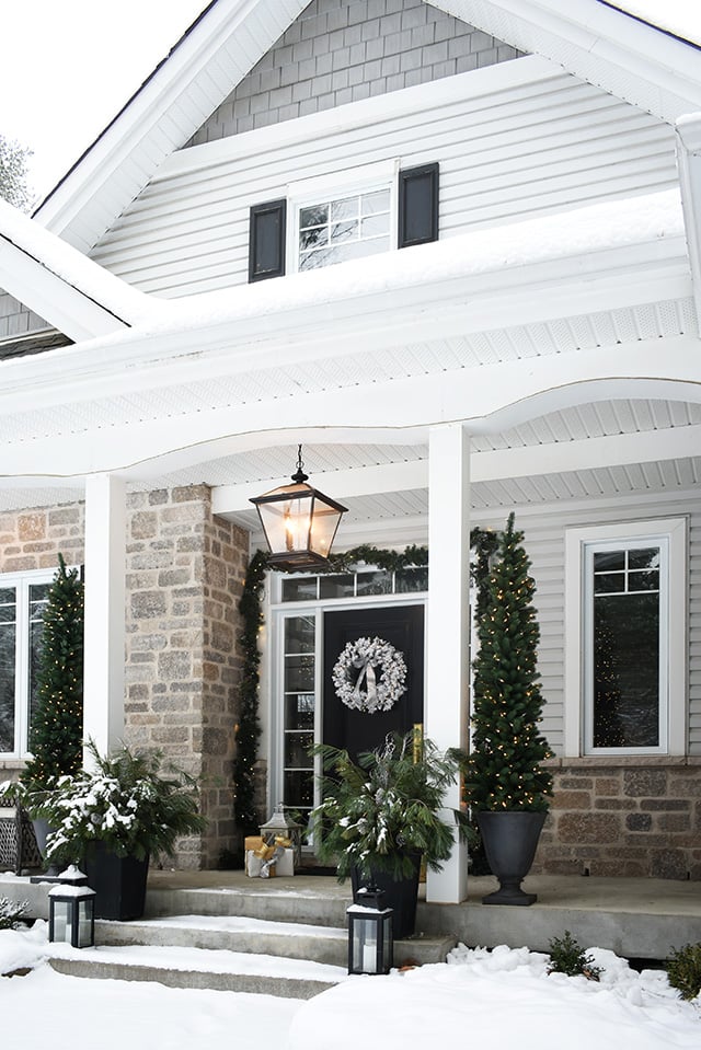 Christmas front porch decorating flocked wreath, garland, pencil trees and planters with fresh cut pine branches.