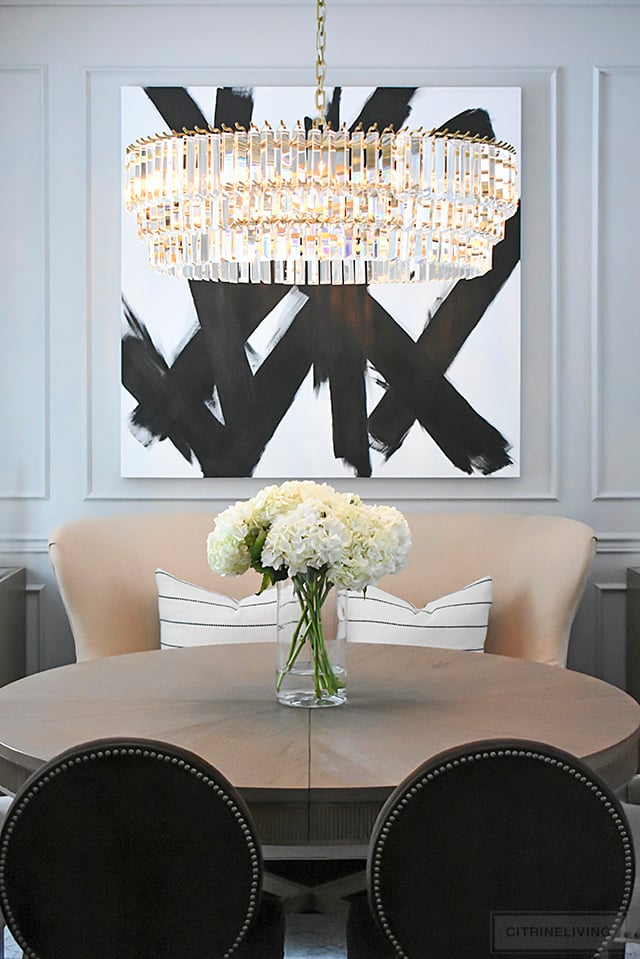 Dining room reveal with stunning crystal chandelier and dramatic black and white artwork makes a bold statement. 