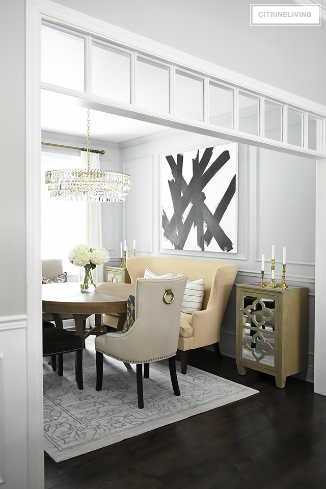 A gorgeous dining room makeover reveal with new gray walls and moldings, painted from the crown to the basboards. A spectacular chandelier sets the tone for this chic, sophisticated, bright and airy look. Dramatic black and white artwork makes a bold statement.