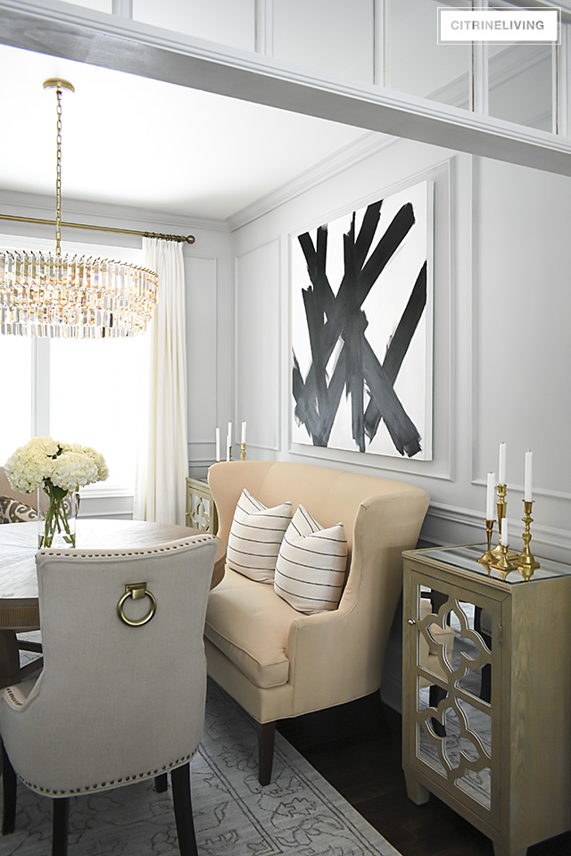 A gorgeous dining room makeover reveal with new gray walls and moldings, painted from the crown to the basboards. A spectacular chandelier sets the tone for this chic, sophisticated, bright and airy look. Dramatic black and white artwork makes a bold statement.