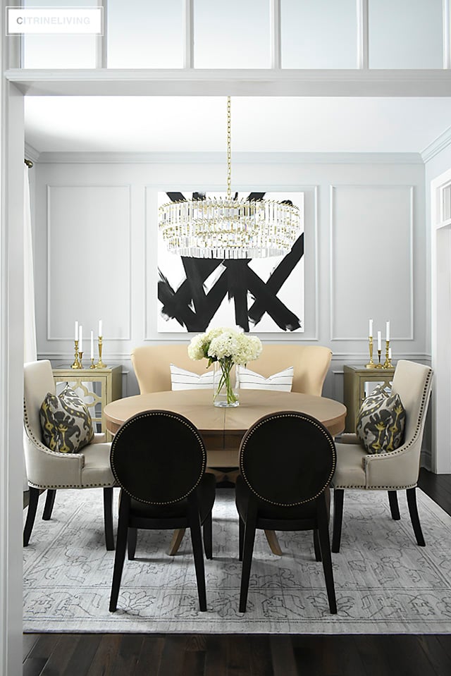 A gorgeous dining room makeover reveal with new gray walls and moldings, painted from the crown to the basboards. A spectacular chandelier sets the tone for this chic, sophisticated, bright and airy look. Dramatic black and white artwork makes a bold statement.