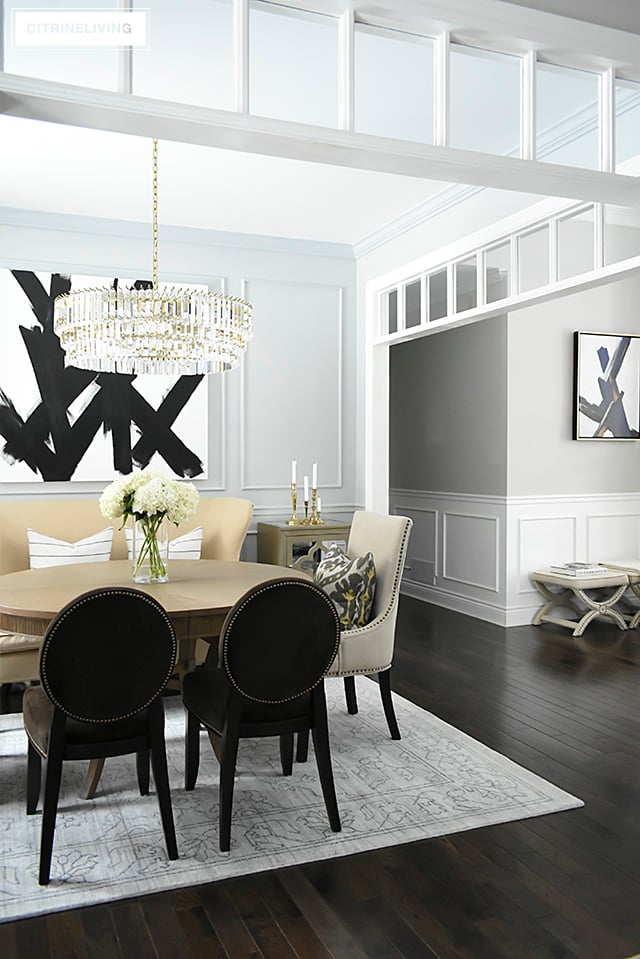 A gorgeous dining room makeover reveal with new gray walls and moldings, painted from the crown to the basboards. A spectacular chandelier sets the tone for this chic, sophisticated, bright and airy look. Dramatic black and white artwork makes a bold statement.