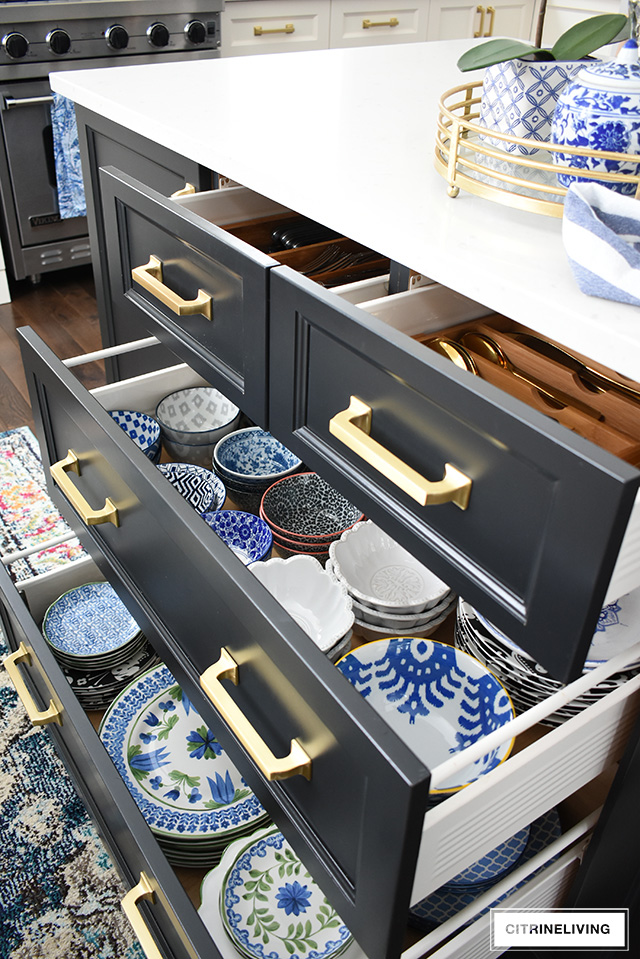 Kitchen drawers with brass pulls, open drawers with beautiful blue and white dishes and bowls.