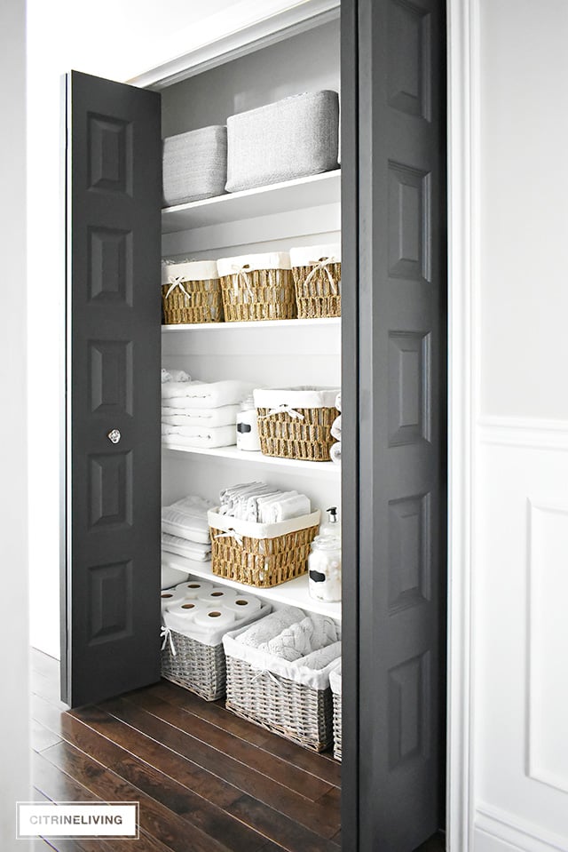 Organized linen closet reveal! A fresh coat of paint, pretty baskets and major purging, it went from messy and cramped to spacious and airy!