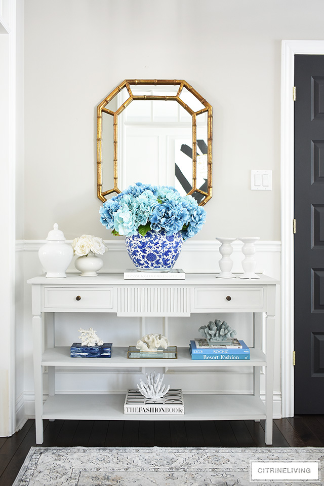 Freshen up your spring entryway decorating with a large blue hydrangea arrangement, coral sculptures, design books and white accessories.