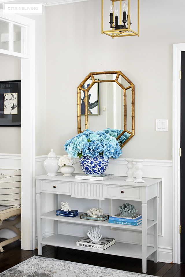 Freshen up your spring entryway decorating with a large blue hydrangea arrangement, coral sculptures, design books and white accessories.