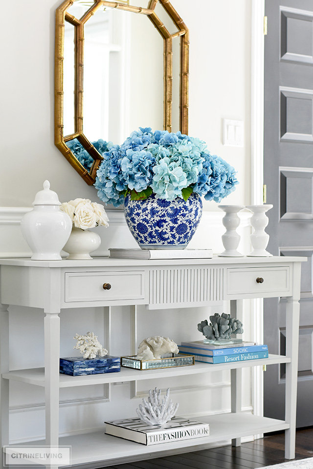 Stunning oversized faux hydrangea arrangement in a large blue and white ginger jar displayed with a gorgeous collection of coral sculptures.
