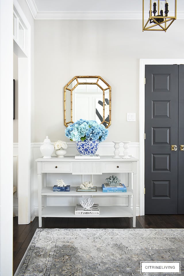 Spring entryway decorating, grey console table with large blue hydrangea arrangement in a blue and white ginger jar.