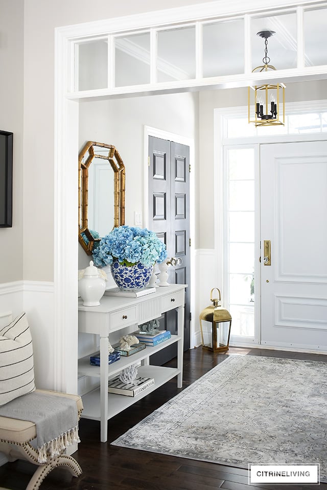 Beautiful spring decorated entryway with a large-scale faux hydrangea arrangement and coral accessories.