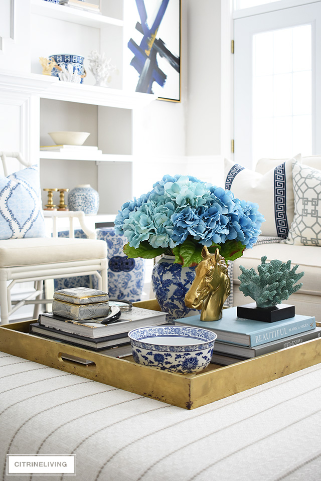 Living room ottoman styled with a blue and white ginger jar and blue hydrangeas, design books, bowls and accessories.