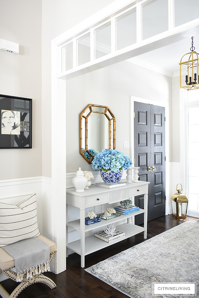 reshen up your spring entryway decorating with a large blue hydrangea arrangement, coral sculptures, design books and white accessories.