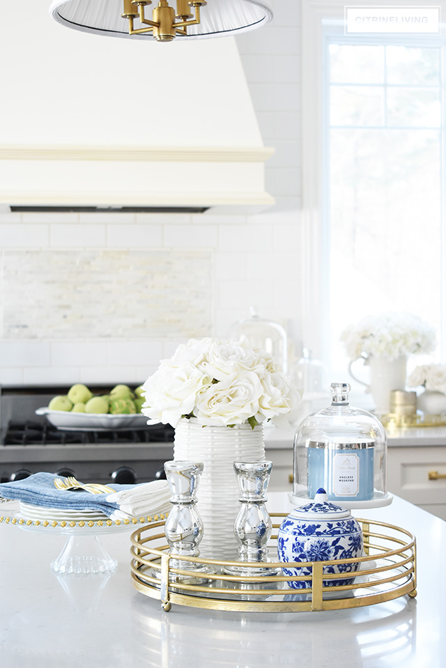 Gorgeous spring decorating ideas for your kitchen - beautiful faux flowers and fruit & blue and white touches are elegant in a timeless kitchen.