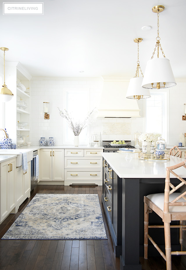 Spring kitchen decorating ideas- gorgeous white and black kitchen with soft blues, a vintage rug and faux florals.