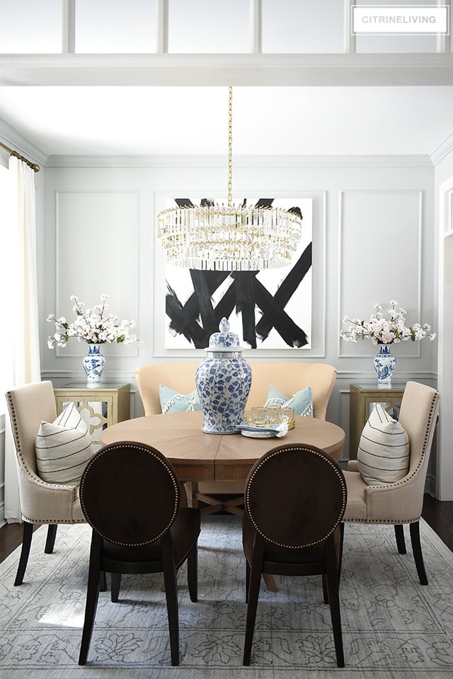 Dining room featuring transom details, modern abstract art, grey walls, moldings, crystal chandelier. Simple spring decorating with blue and white chinoiserie and faux cherry blossoms.