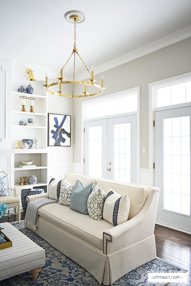 Elegant living room with skirted white sofa, vintage inspired rug and brass chandelier.