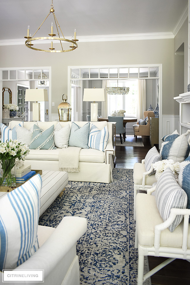 Gorgeous open concept living room with a soft and elegant summer color palette - light blue and white, and creamy tones with touches of brass.