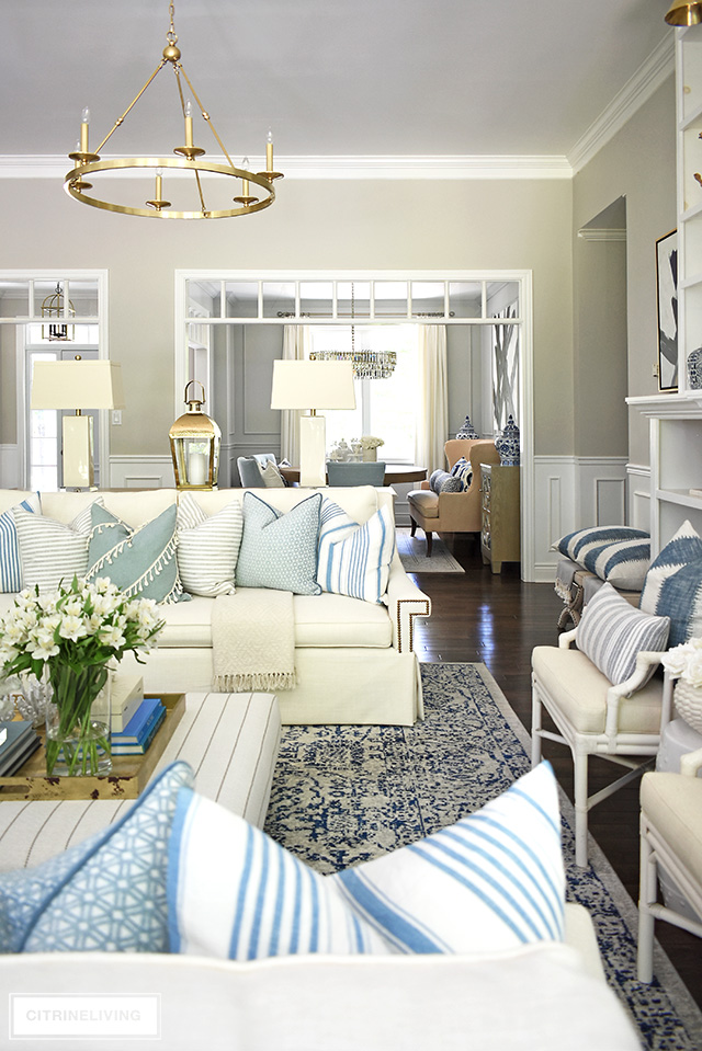 Cosy yet elegant living room styled for summer with a beach-chic vive using light blue and white, stripes and mixed patterns.