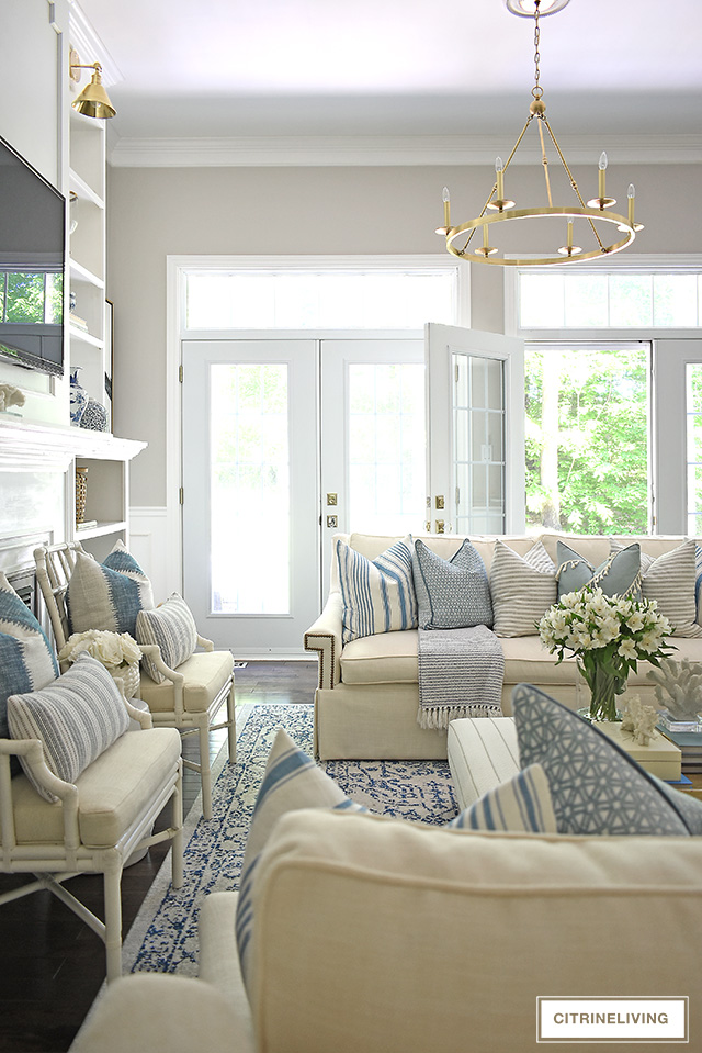 Gorgeous living room with white sofas, blue and white striped pillows and layered textures for an airy summer, coastal chic look.