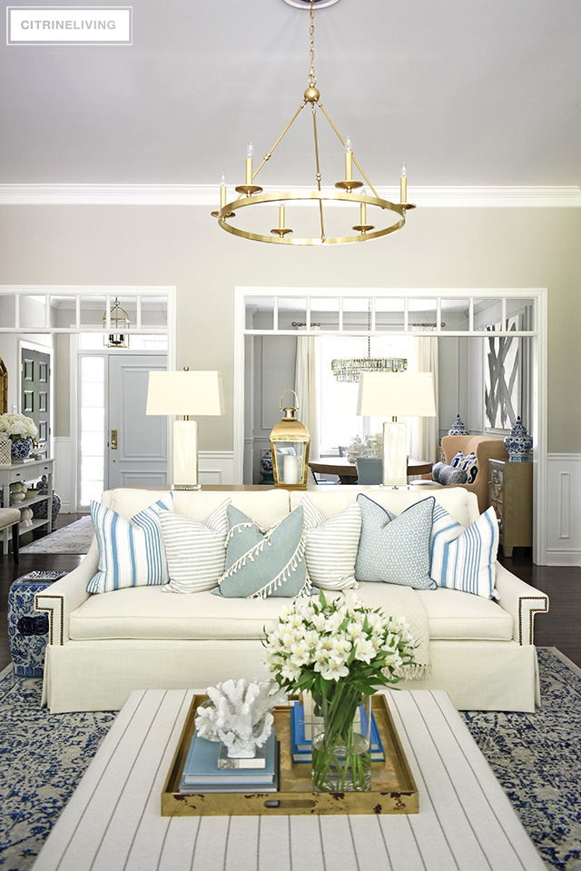 Summer decorating with white sofas, light blue and white color palette and layers of coral sculptures bring a relaxed beach look to this beautiful living room.