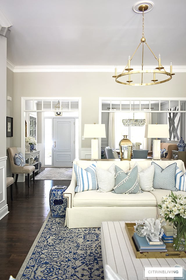 Open concept living room decorated for summer with a light and crisp color palette using blue and white, with stripes and mixed patterns for chic beach look.