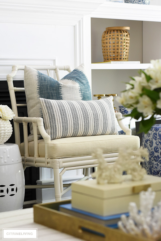 White rattan accent chair with layered striped pillows create a relaxed coastal look.