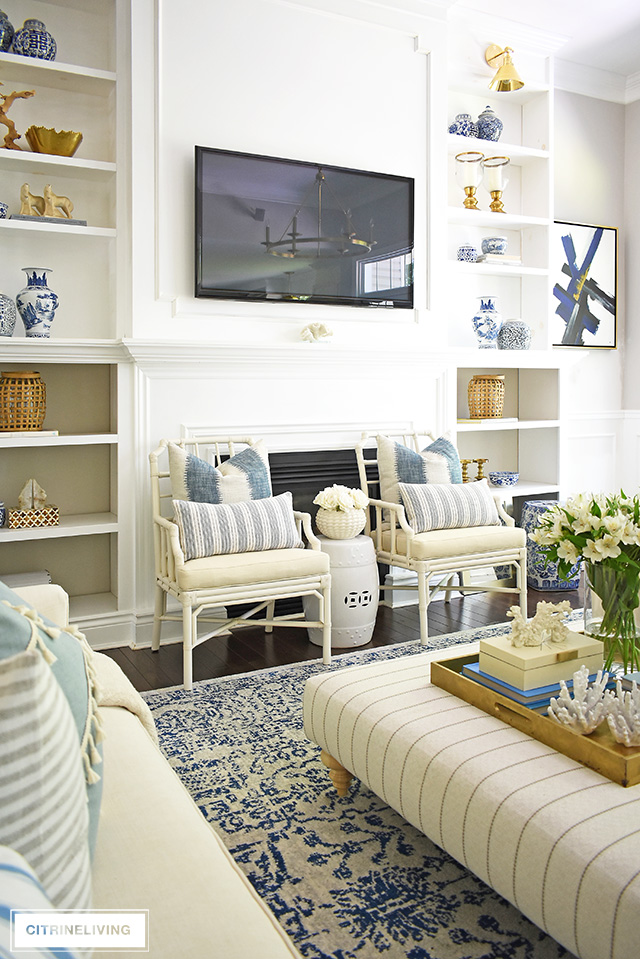 Beautiful built-in bookshelves, decorated for summer with blue and white accessories, woven lanterns an brass details. 