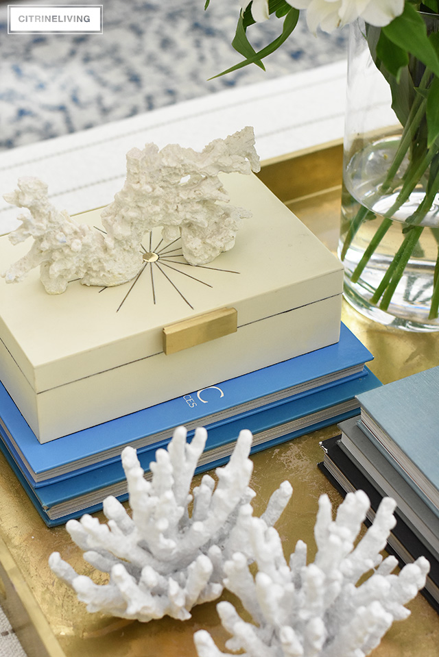 Summer decorating and styling with layers of coral sculptures, design books and decorative boxes for added visual interest.