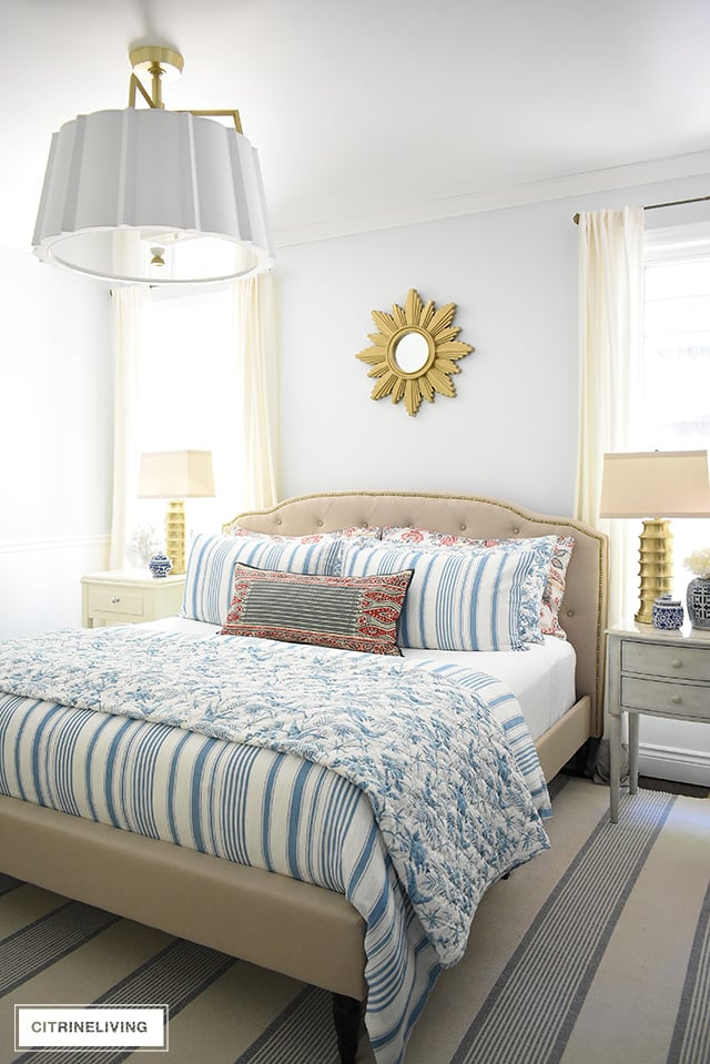 Bedroom styled with a coastal feel in blues and reds is chic and sophisticated.