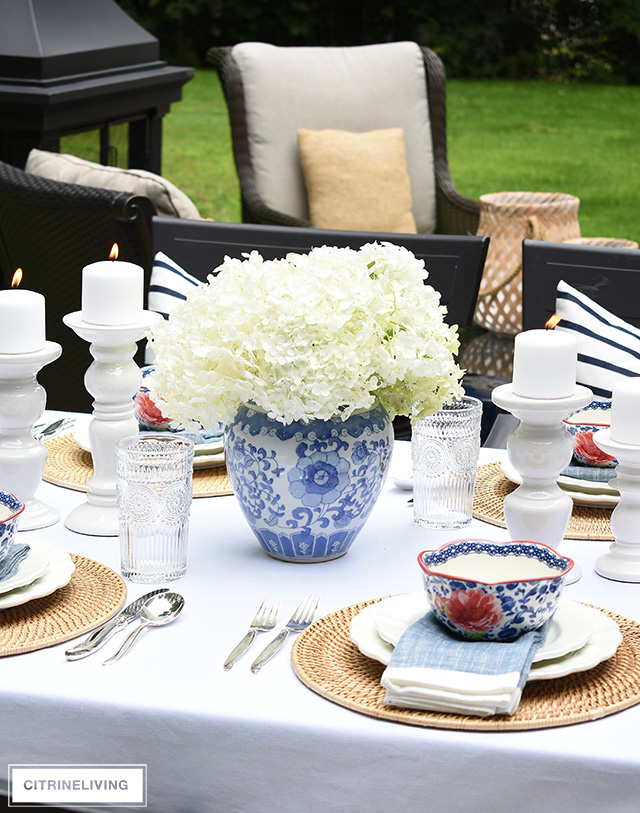 Outdoor late summer tablescape with blue and white vase and hydrangeas.