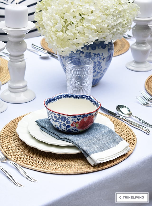 Vintage inspired outdoor late summer tablescape with white scalloped dishes and blue and white bowls.