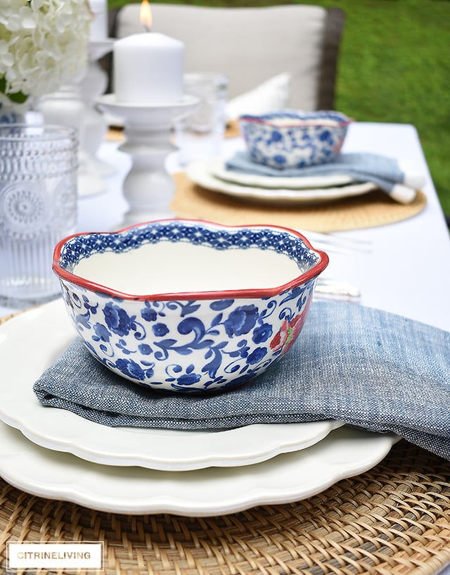 Vintage inspired outdoor late summer tablescape with white scalloped dishes and blue and white bowls.