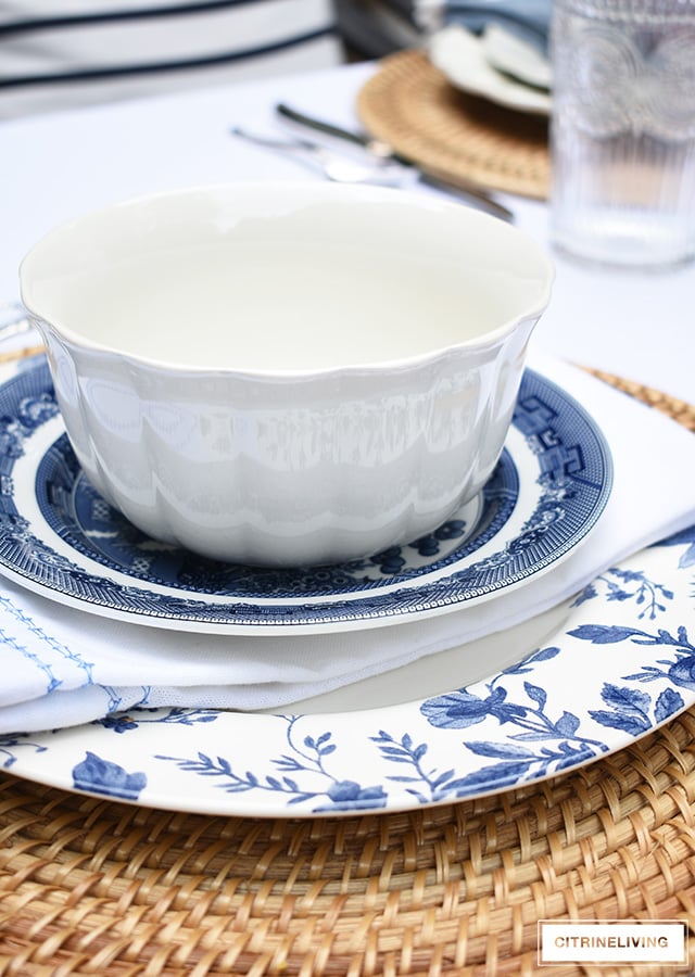 Vintage inspired outdoor late summer tablescape with white scalloped dishes and blue and white bowls.