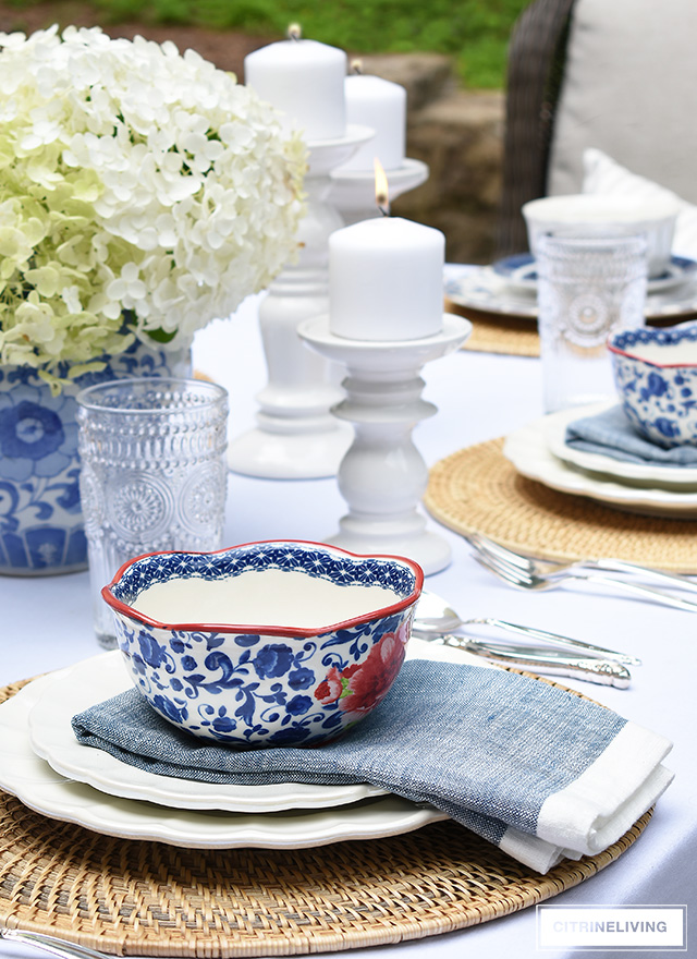 Vintage inspired outdoor late summer tablescape with white scalloped dishes and blue and white bowls.