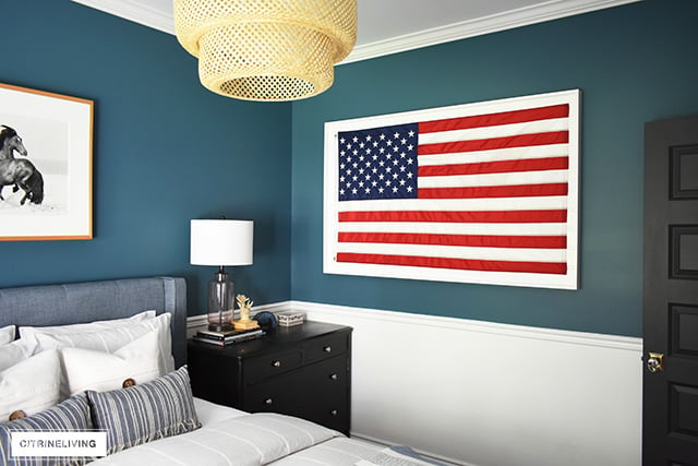 Modern coastal bedroom with American flag, striped bedding and sea-insured accessories.