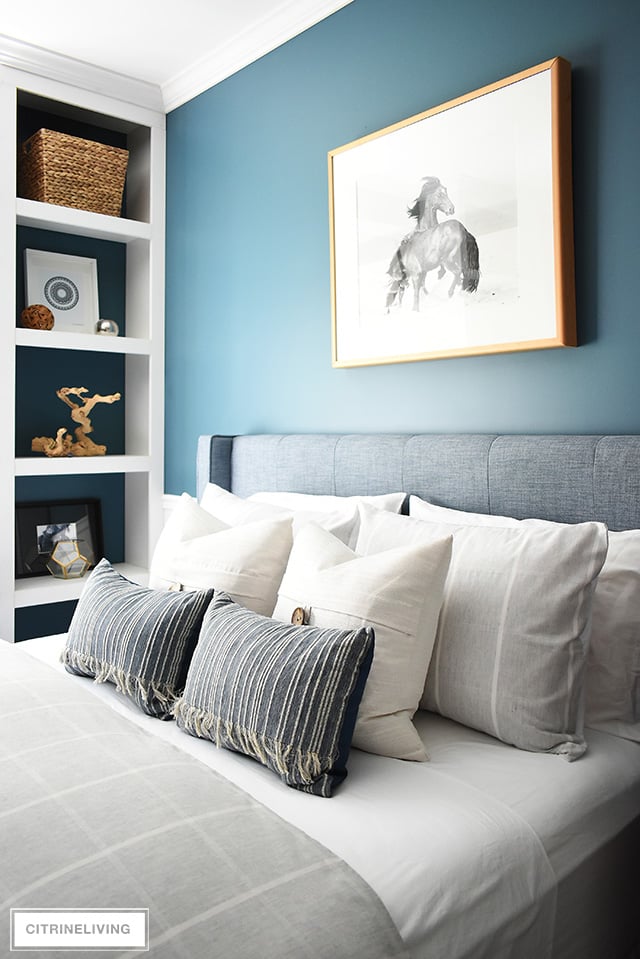 Modern coastal teen bedroom with simple striped bedding in light tones and open shelves with modern art and decor.