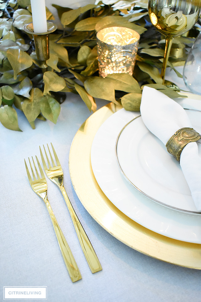 Beautiful luxe fall tablescape with gold charger plates, flatware and faux gold leaves as the centrepiece. Vintage brass napkin rings add a layer of nostalgia.