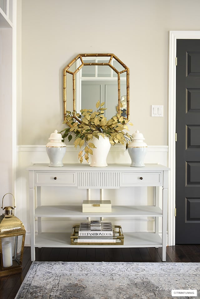 Gorgeous fall entryway table styled with faux gold leaves, ginger jars, decorative box, brass + lucite tray.