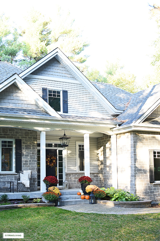 Fall decorated front porch with beautiful lush mums and scattered pumpkins to welcome your guests.