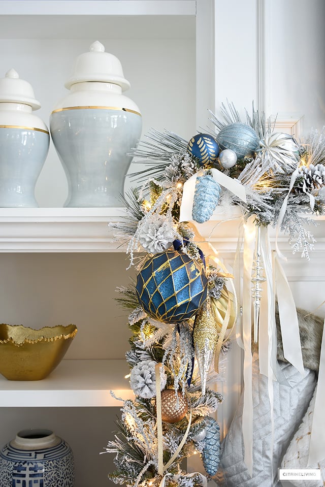 Christmas mantel with flocked garland, blue and gold decorations, ginger jars