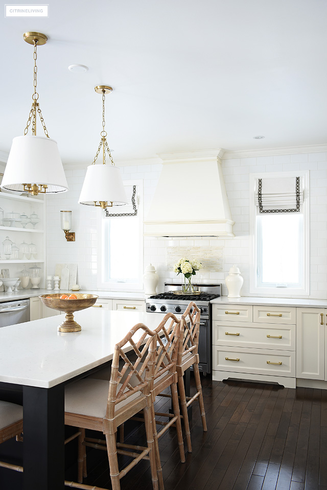 Traditional kitchen with brass accents, Chinese Chippendale stools and custom roman shades on windows.