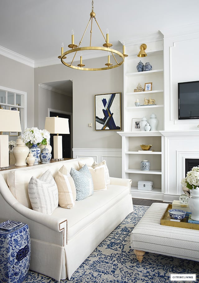 Living room decorating for spring with beautiful pillows, ginger jars, blue and white accents and faux floral arrangements.