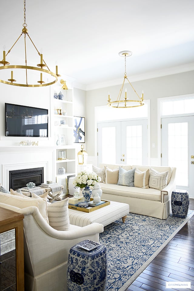 Spring living room decorating with gorgeous pillows, faux flowers and blue and white accents.