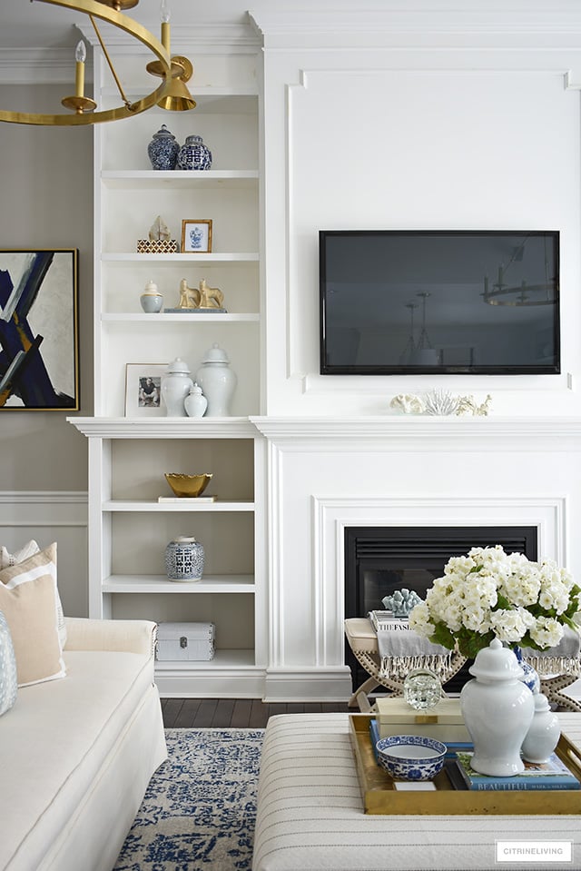 Spring decorating ideas for bookshelves with ginger jars, blue and white pottery and brass accents.