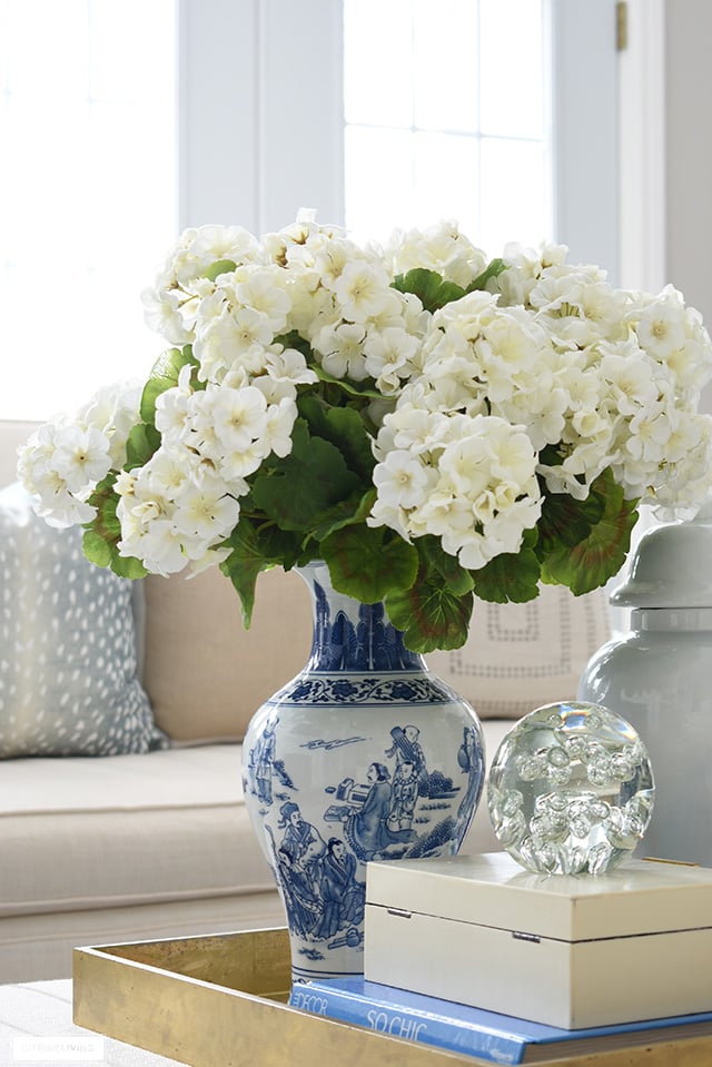 Gorgeous coffee table styling with gold tray, faux flowers, blue and white, design books and chic accessories.