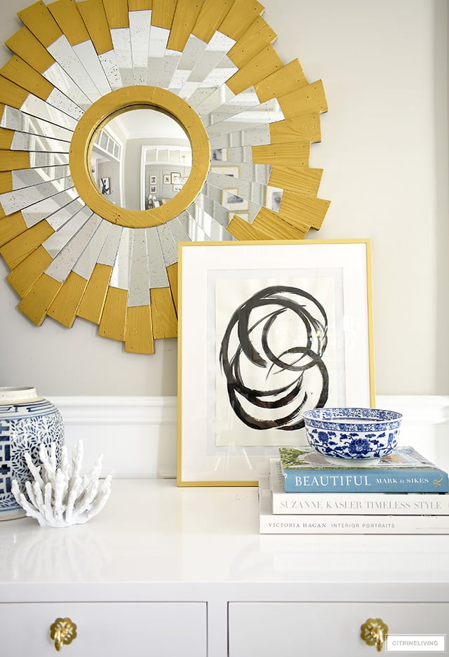 A chic and pretty console table vignette with abstract art, blue and white chinoiserie, design books and a pretty coral sculpture.