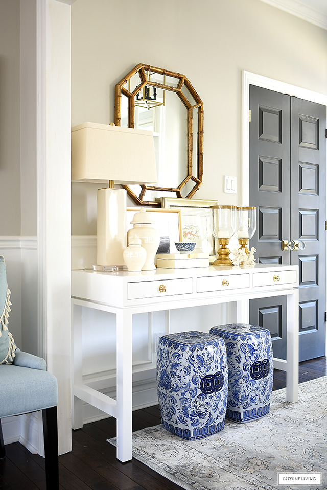 A coastal-chic console table styled with blue and white garden stools and layers of neutral accessories.