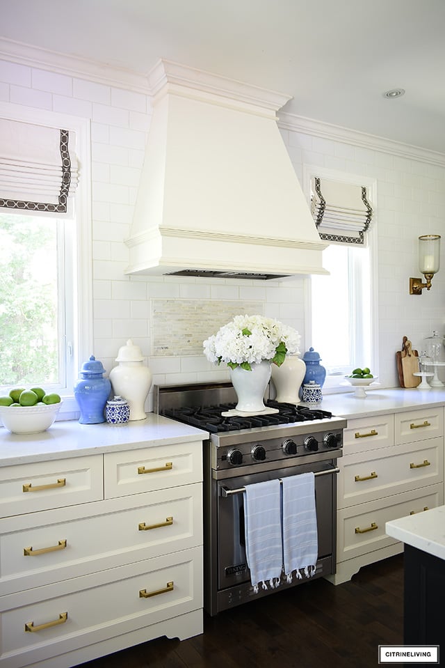 Summer kitchen decorating - ginger jars flanking the stove with a faux hydrangea arrangement styled on a marble tray on top.