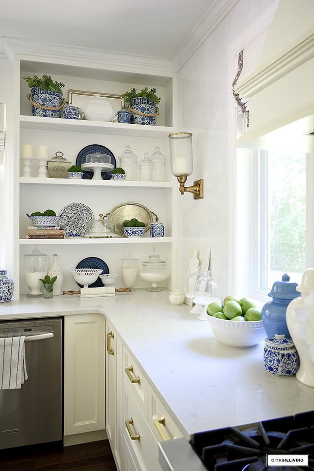 Summer decorating in the kitchen - shelving with blue and white bowls, dishes and jars, with touches of greenery for summer.