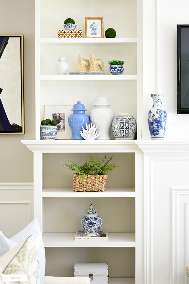 Bookshelves decorated for summer with beautiful blue ginger jars, blue and white chinoiserie, greenery and natural elements.