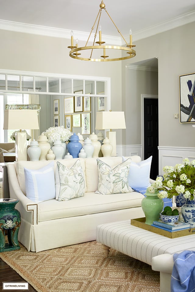 Living room decor, white sofa decorated with beautiful floral pillows, light blue pillows. Gorgeous jute rug and blue and green accents are perfect for summer!